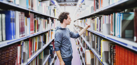 Man standing between the shelves of a library