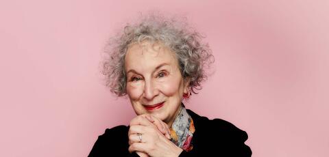 Women with curly grey hair clasping her hands at chin