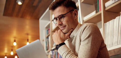 white male viewing laptop screen in a library