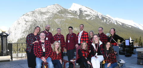 Group of people wearing lumberjack shirts infront of mountian
