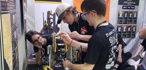 Students working on a robot in a shop