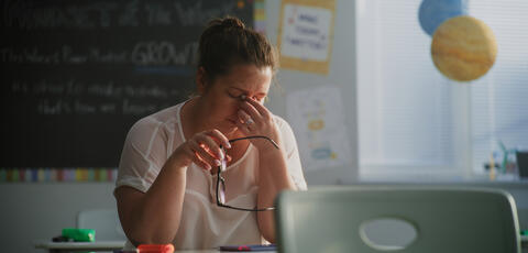 Tired teacher sitting at a desk