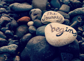 "The Journey Begins" written on rocks