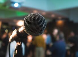A close-up shot of a microphone on a stage in front of a blurry crowd