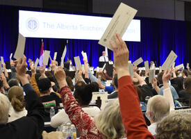 Attendees at annual assembly vote with arms raised and tickets in hand.