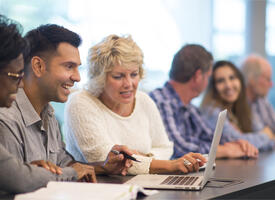 Group of people talking while seated at a long table
