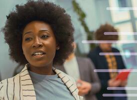 Black women in striped beige blazer pointing at a board, leading an activity