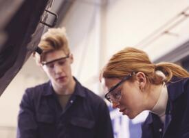 A pair of mechanics examines a car