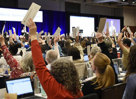 Room full of individuals voting with their hands raised at the 2022 Annual Representative Assembly