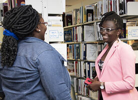 Two people speak in a library