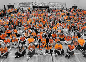 School assembly with children wearing orange t-shirts 