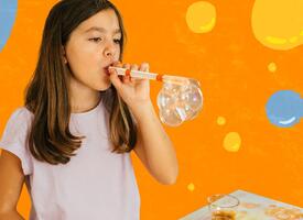 Girl blowing bubbles through a straw