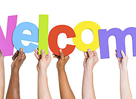 Hands hold up a welcome sign