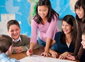 Kids at a table with a map in that background