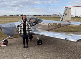 Women standing next to a small silver airplane