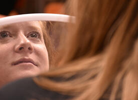 Participant in a makeup session at a teacher's convention looks into a mirror