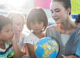 A teacher shows a globe to her students