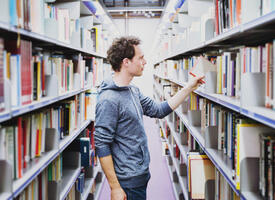Man standing between the shelves of a library
