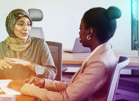 Two BIPOC women meeting at a table