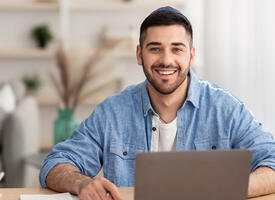 Young man sits infront of laptop