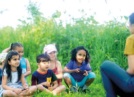 A teacher speaks to students in an outdoor setting
