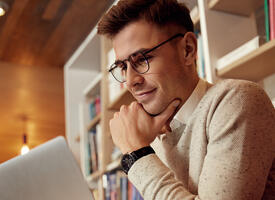 white male viewing laptop screen in a library