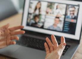 Someone explaining with their hands to a group online chat
