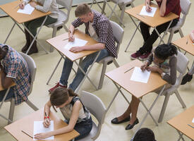 Aerial image of students writing a test in rows of desks