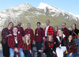 Group of people wearing lumberjack shirts infront of mountian
