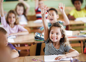 A couple of elementary students raising their hands eagerly to speak french