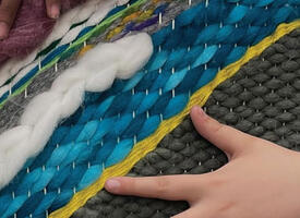 Kids hands feeling a woven fabric with many colours and textures