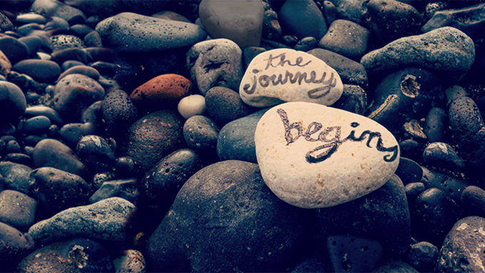 "The Journey Begins" written on rocks