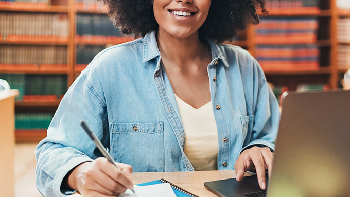 Photo of woman working on her laptop in a library