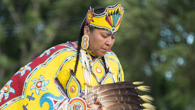 Indigenous woman in regalia dancing in a pow wow.