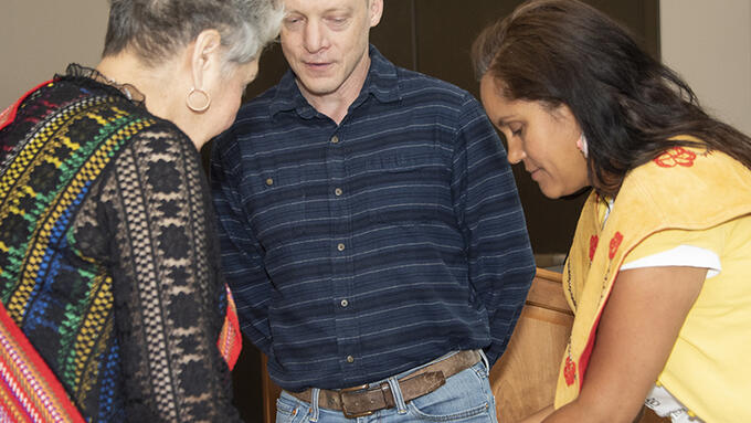 Three people participating in a smudging ceremony.