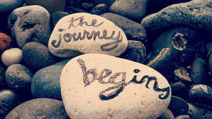 River rocks with the journey begins written on them
