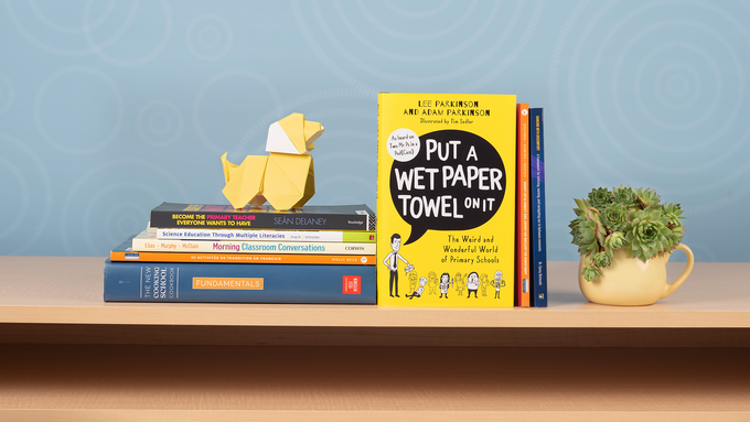 Books displayed on a shelf in front of a blue background with an origami dog and coffee cup with a succulent plant.