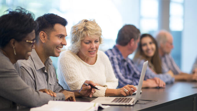 Group of people talking while seated at a long table