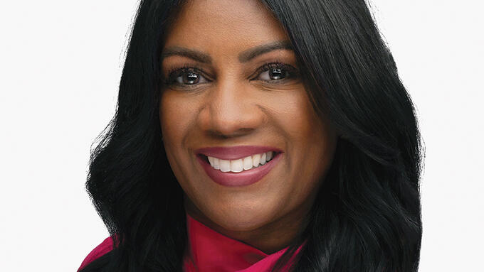 Portrait of a smiling black women with long black hair in a fuscia blouse. 