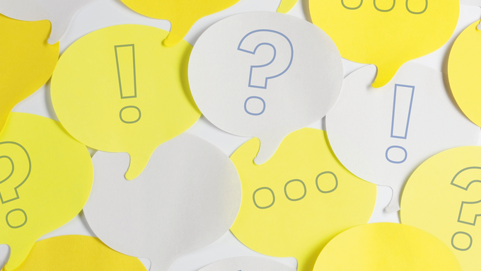White and yellow speech bubble post-it notes with hand drawn ellipses, question and exclamation marks,