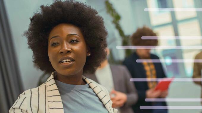 Black women in striped beige blazer pointing at a board, leading an activity