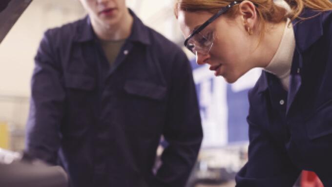 A pair of mechanics examines a car