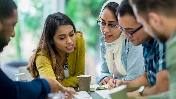 Diverse group seated at table reviewing documents