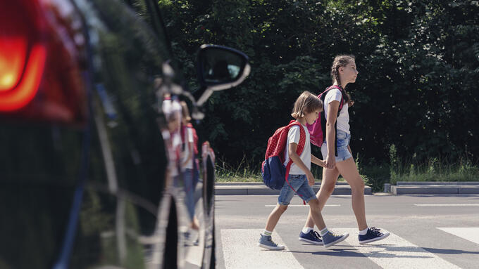Two children crossing at crosswalk in front of car
