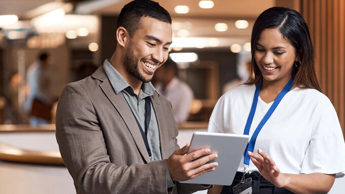 Man and women wearing lanyards looking at a table in a hall
