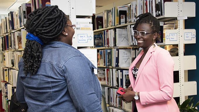 Two people speak in a library