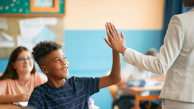 A young black student giving a high five to a teacher
