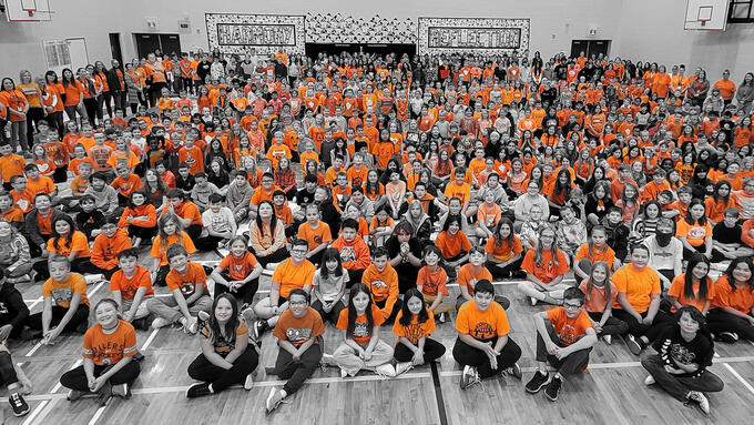 School assembly with children wearing orange t-shirts 