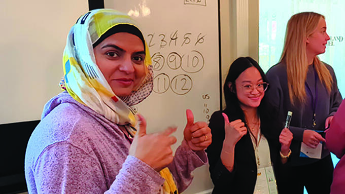 Two teachers give a thumbs up at the Beginning Teachers' Conference