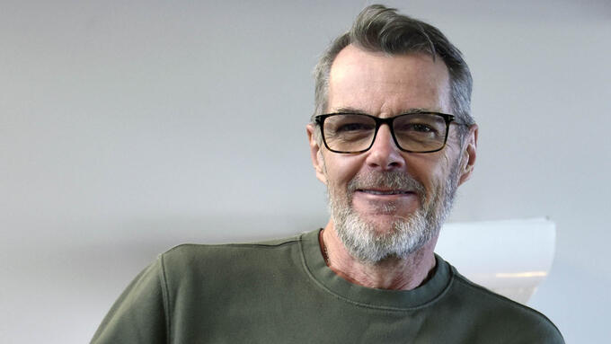 Man in 60's wearing a green sweater, beard and glasses